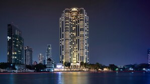 A high-rise hotel with multiple floors, a well-lit facade, and a view of the surrounding cityscape and water.