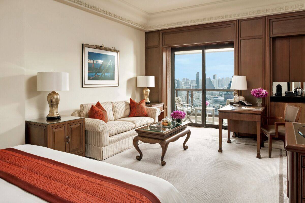 Ein Hotelzimmer mit Bett, Sofa, Schreibtisch und Blick auf die Stadt.