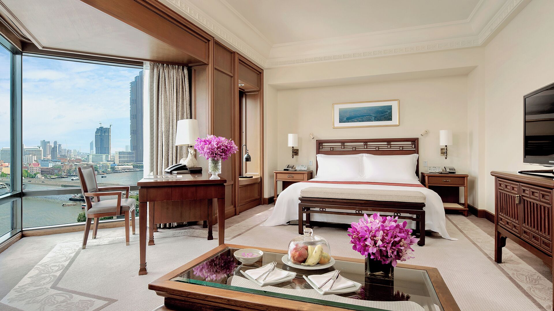 A hotel room with a bed, a desk, a chair, a coffee table, and a TV.