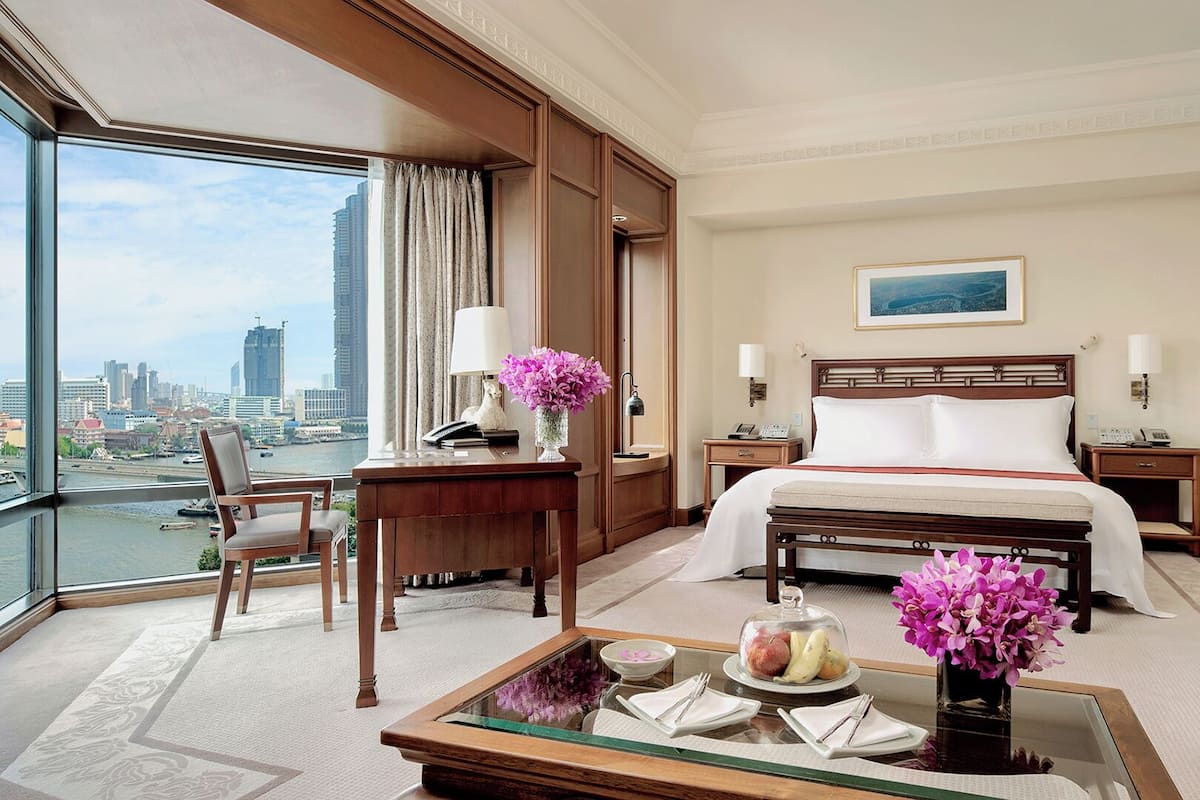 A hotel room with a bed, a desk, a chair, a coffee table, and a TV.