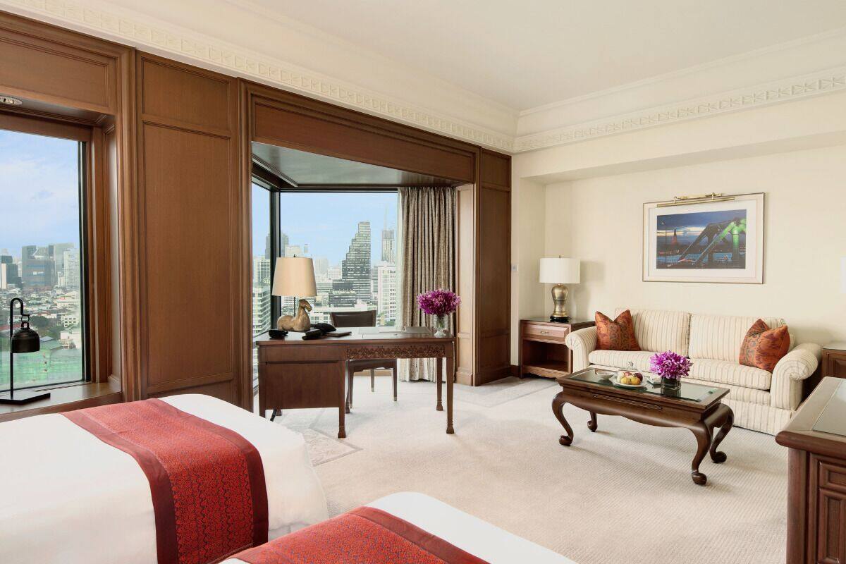 Ein Hotelzimmer mit einem großen Bett, einem Schreibtisch, einer Couch und Blick auf die Stadtlandschaft.