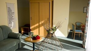 Una habitación con sofá, una mesa con un florero y un armario de madera.