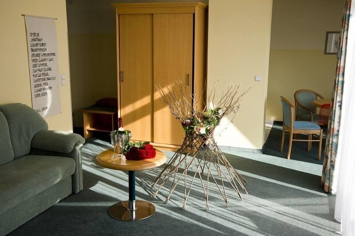 A room with a sofa, a table with a vase of flowers, and a wooden wardrobe.