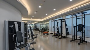 Een moderne sportschool met diverse fitnessapparaten, grote ramen en een schoon, goed verlicht interieur.