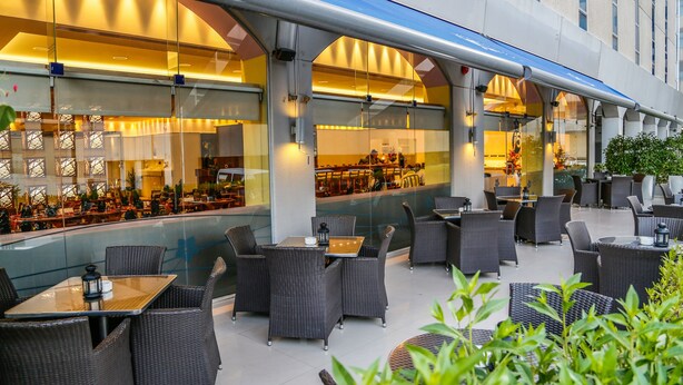 Een terras met wicker meubels en glazen scheidingswanden.