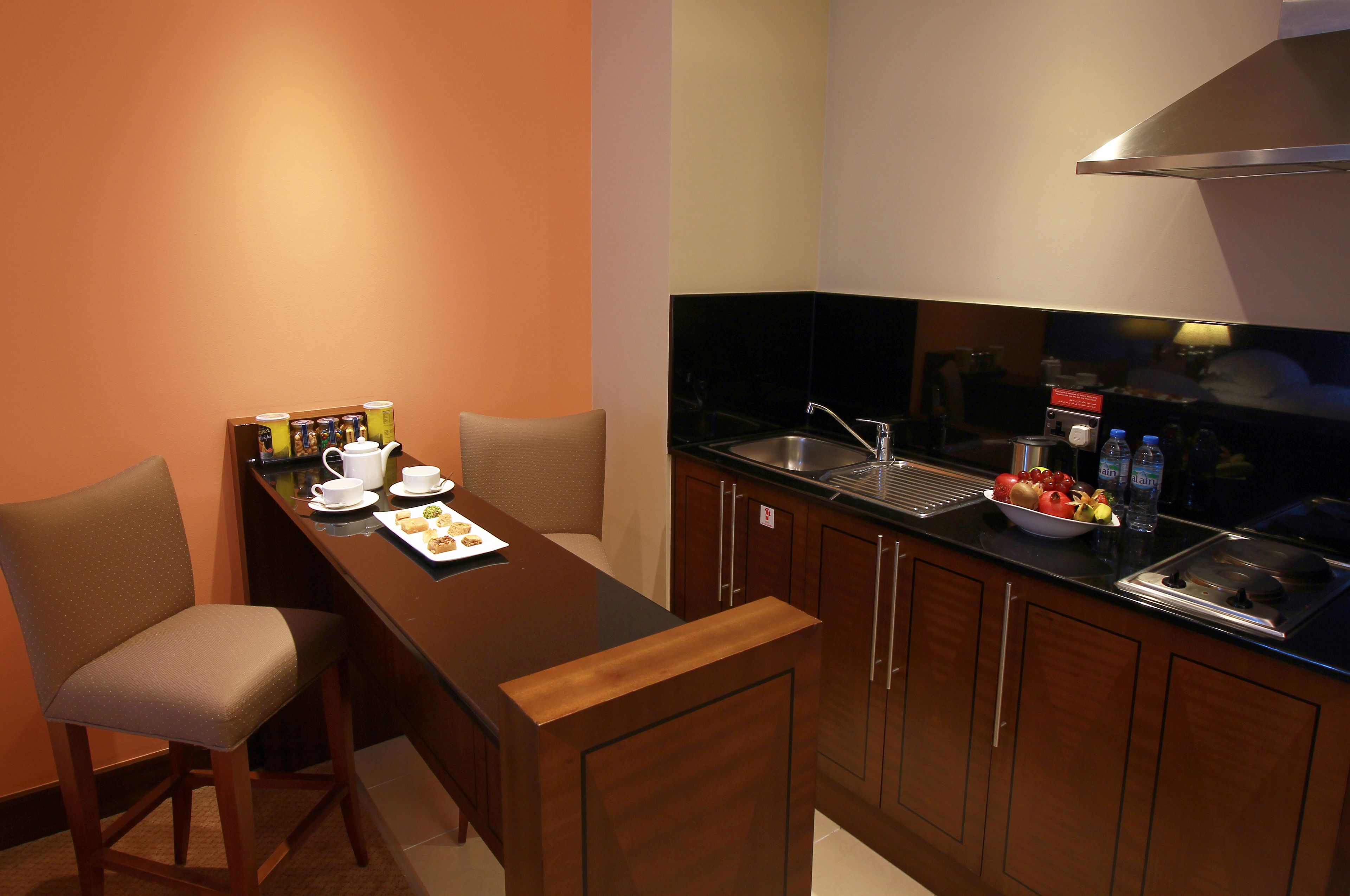 A compact kitchen with a dining area, equipped with a sink, countertop, and a chair.