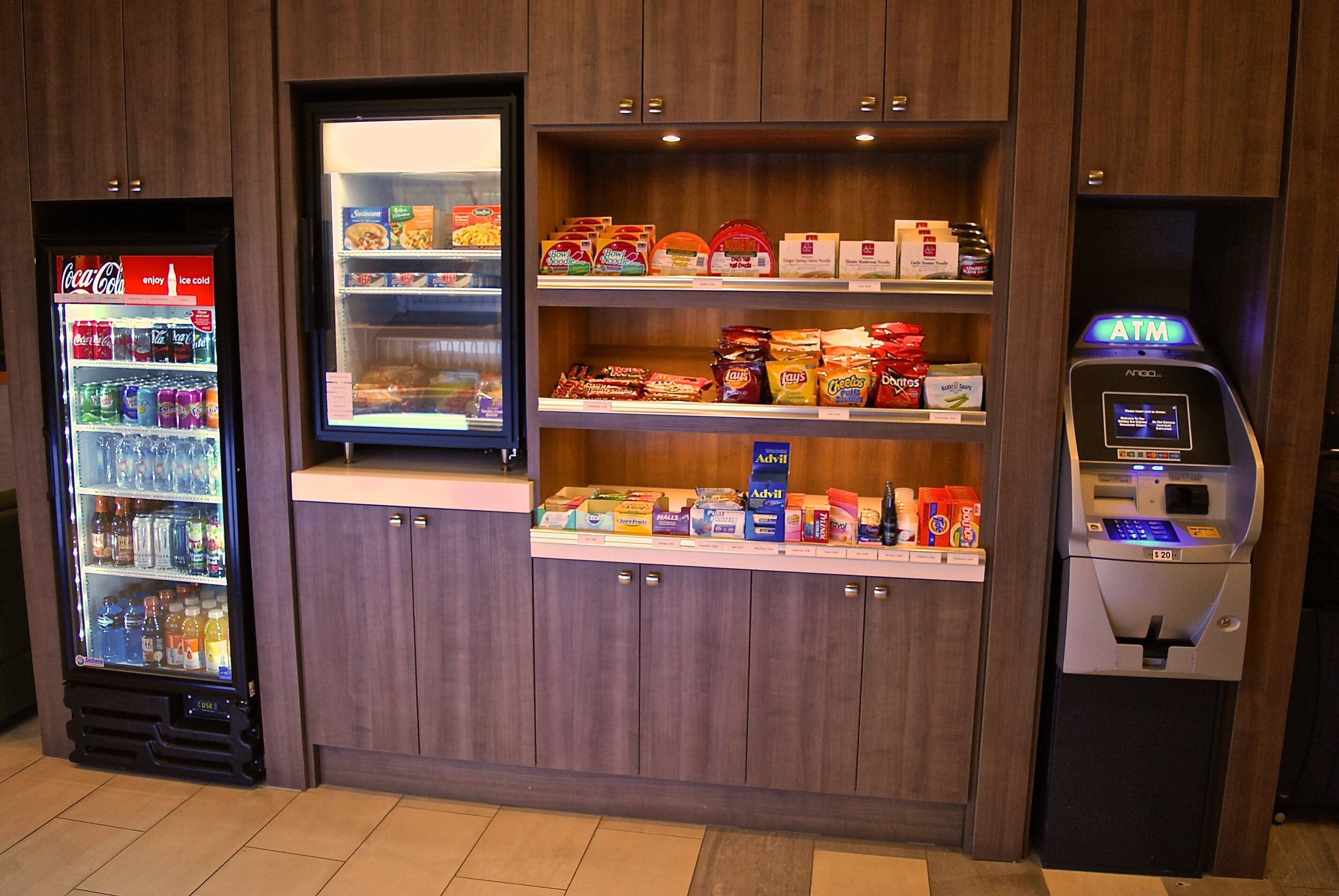 A vending machine area with snacks, a Coca-Cola cooler, and an ATM.