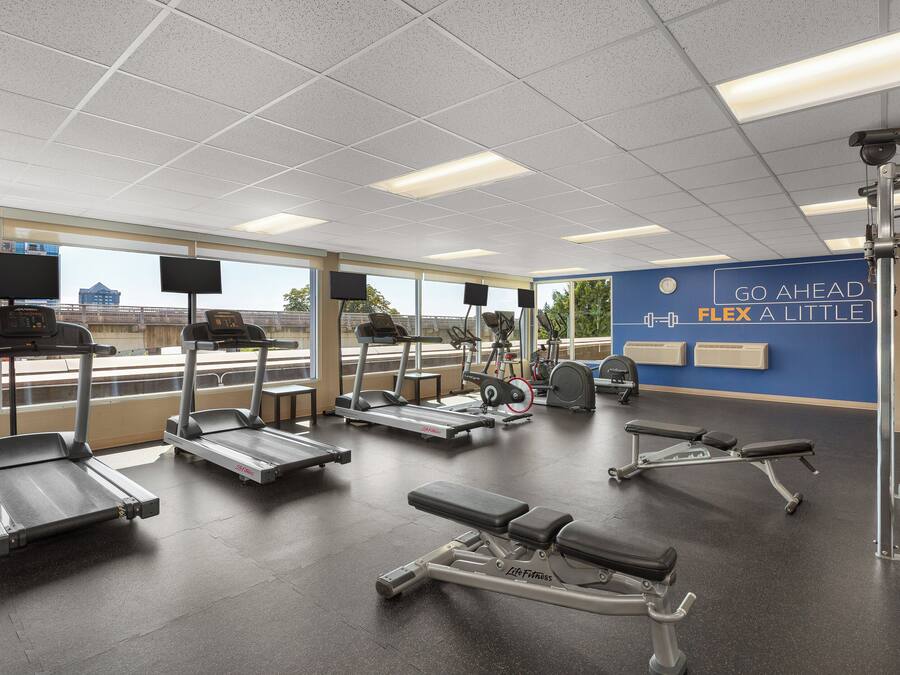 Ein Fitnessstudio mit Laufbändern, Crosstrainern und Gewichtsbänken.