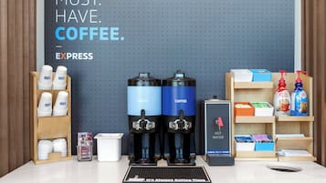 A coffee station with two coffee dispensers, a hot water dispenser, and a coffee maker. There are cups and a coffee maker on the counter.