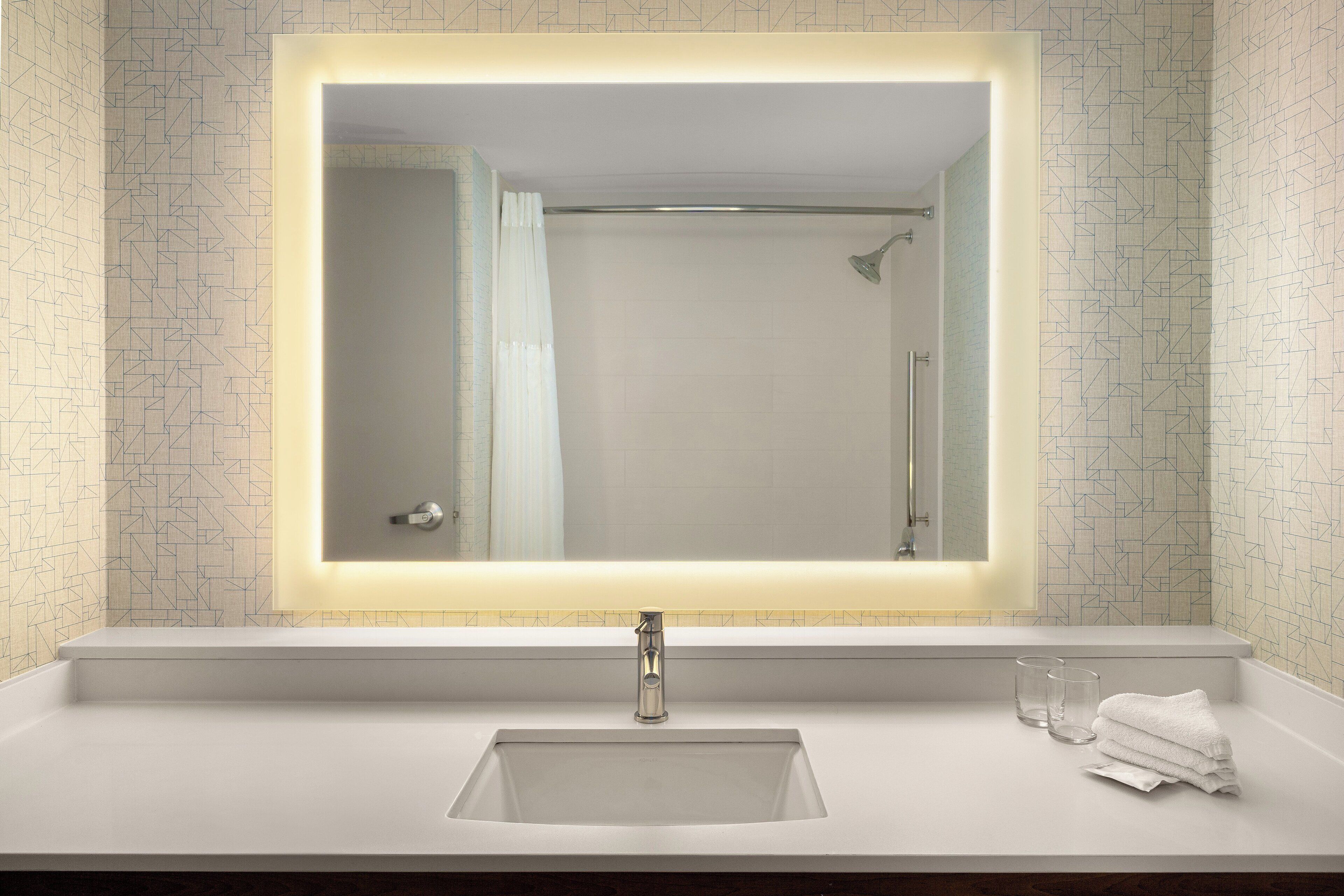 Un baño con un espejo grande, un lavabo y una ducha.