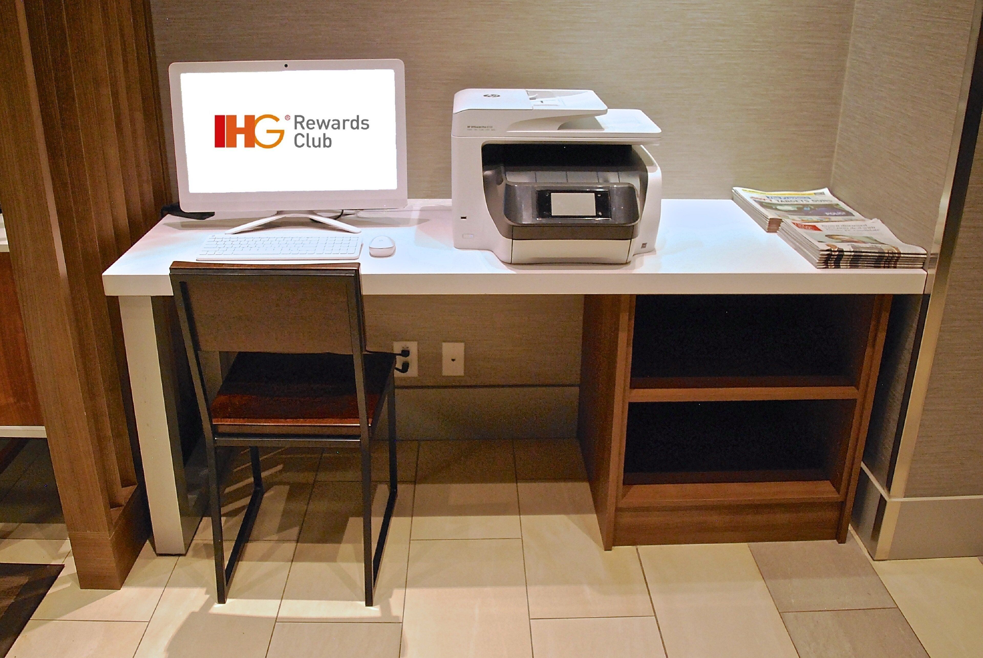 Un escritorio con una computadora, una impresora y una silla.