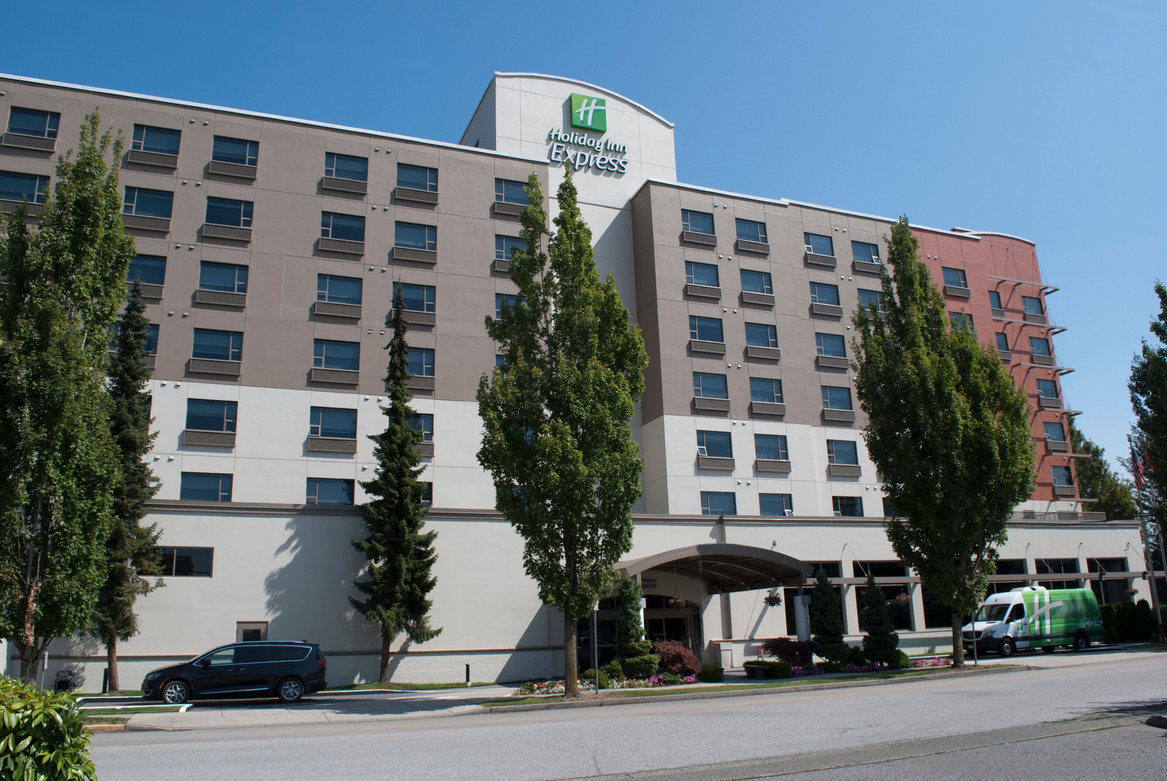 Ein Holiday Inn Express Hotel mit modernem Design, das ein Flachdach, viele Fenster und einen zentralen Eingang zeigt.