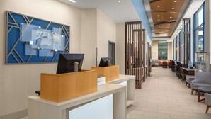 Un'area reception di un hotel dal design moderno, con una scrivania, una zona salotto e un'ampia parete blu con motivi geometrici.