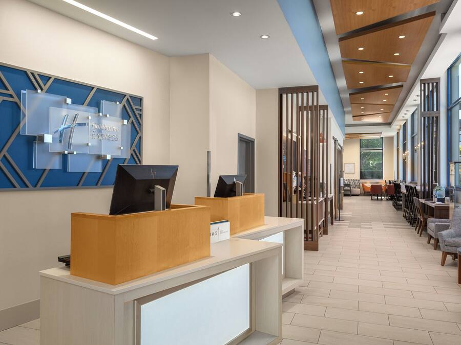 A hotel lobby with a reception desk, seating area, and large windows.