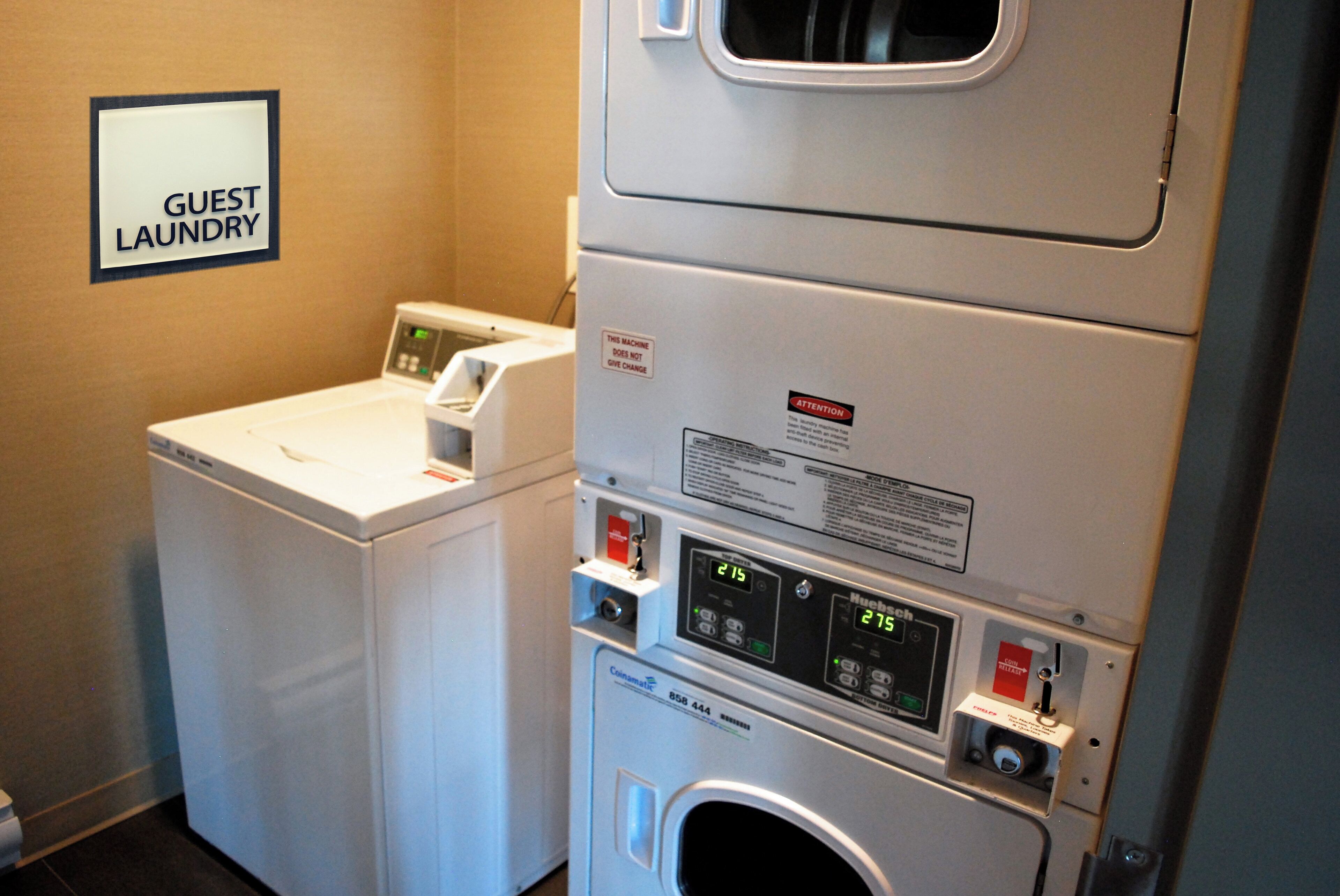 Een hotelwasserette met een bord waarop 'GANG LAUNDRY' staat, en een gestapelde was- en droogmachine.