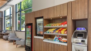A modern interior with seating, a refrigerator stocked with beverages, snack shelves, and an ATM. - Holiday Inn Express Vancouver Airport Richmond by IHG (Richmond)