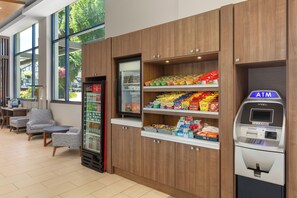 Un espace intérieur moderne comprenant des sièges, un réfrigérateur rempli de boissons, des étagères pour les collations et un distributeur automatique de billets.