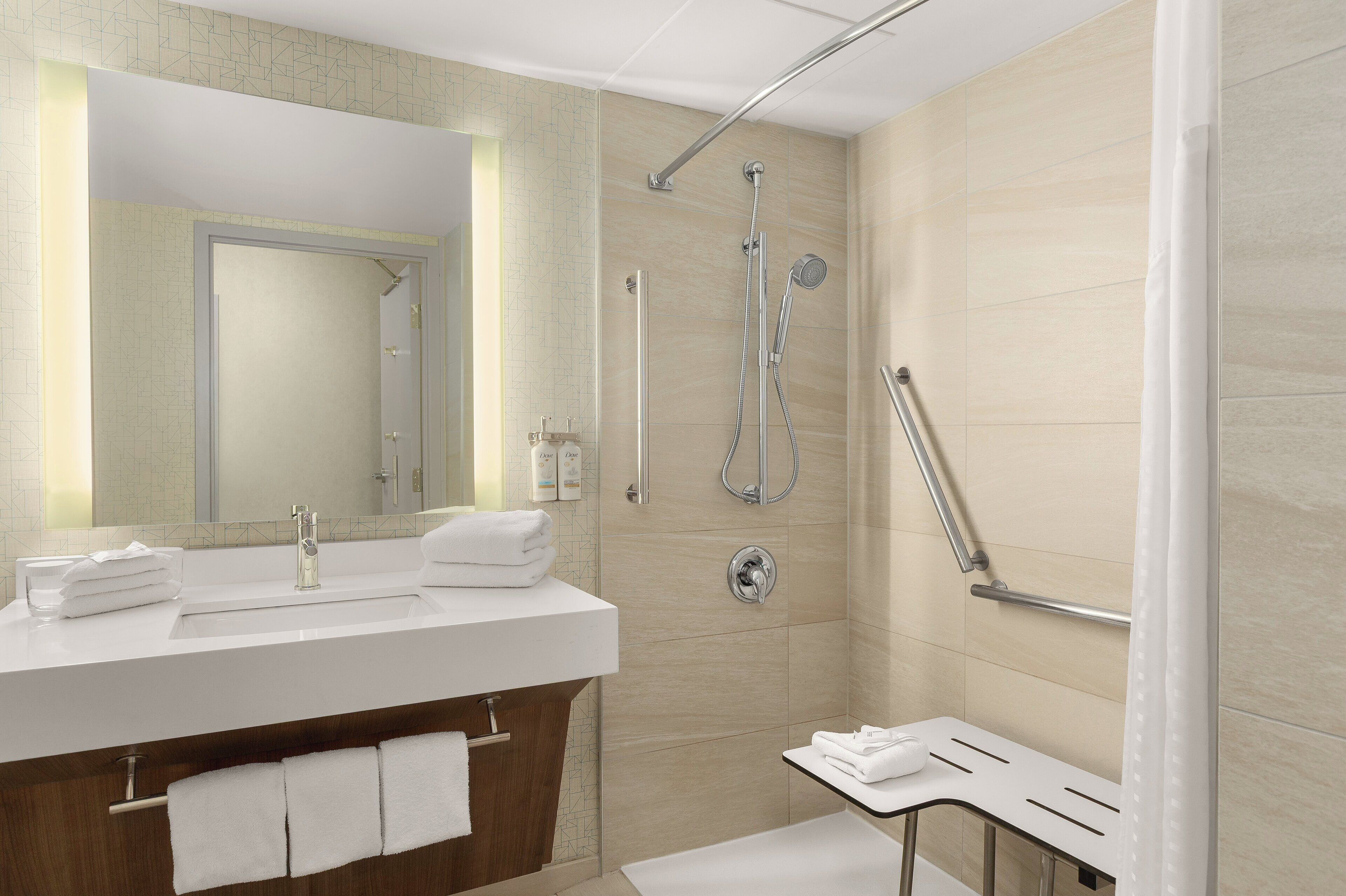 Un baño moderno con un espejo grande, un lavamanos y una zona de ducha.