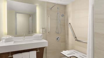 Un baño moderno con un espejo grande, un lavamanos y una zona de ducha.