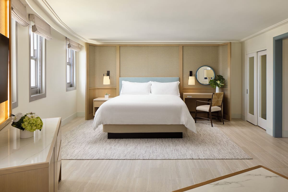 Une chambre d’hôtel moderne avec un grand lit, des tables de chevet, un bureau et une chaise.