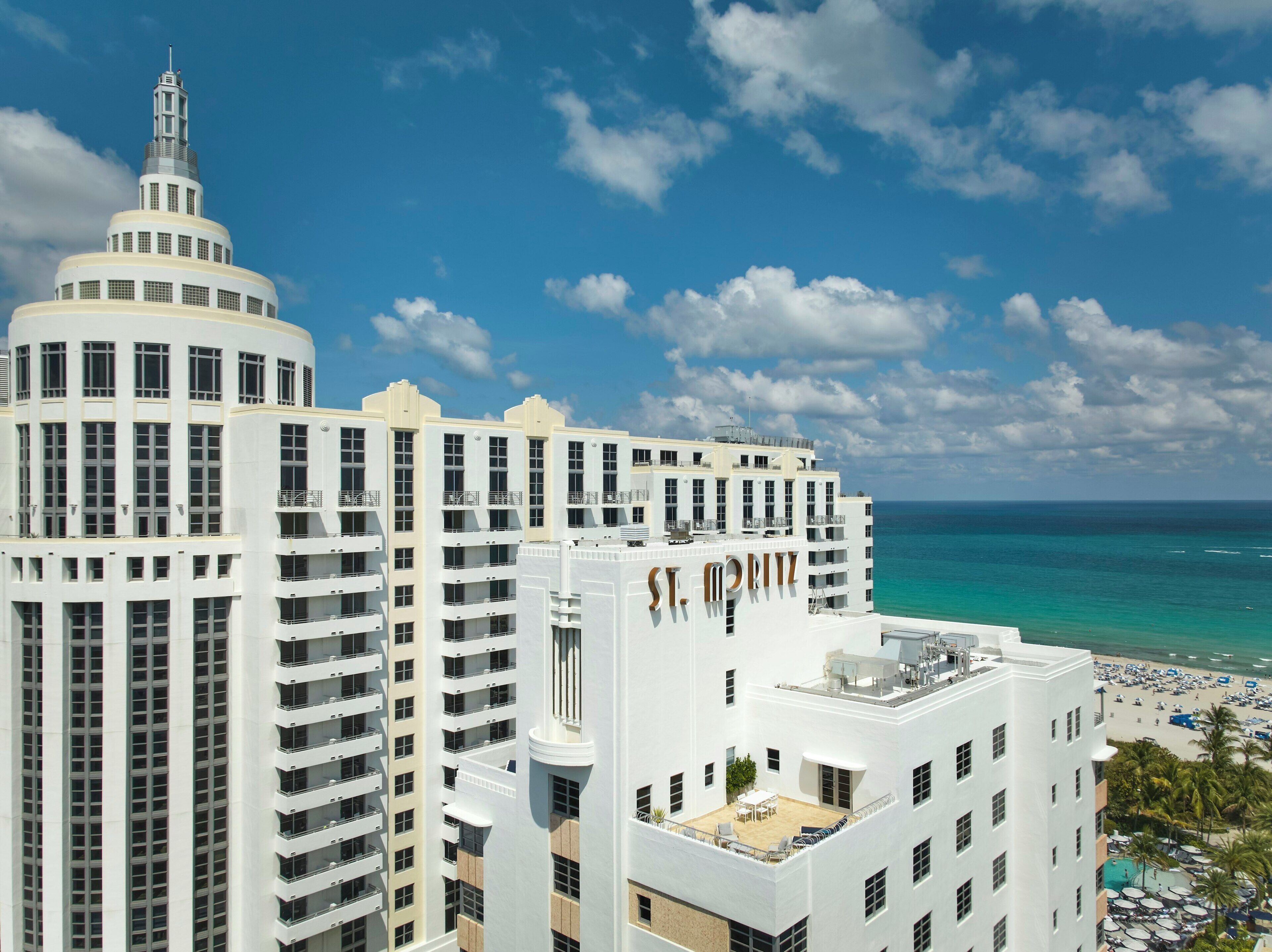 A multi-story hotel with a prominent tower, balconies, and a beach view.
