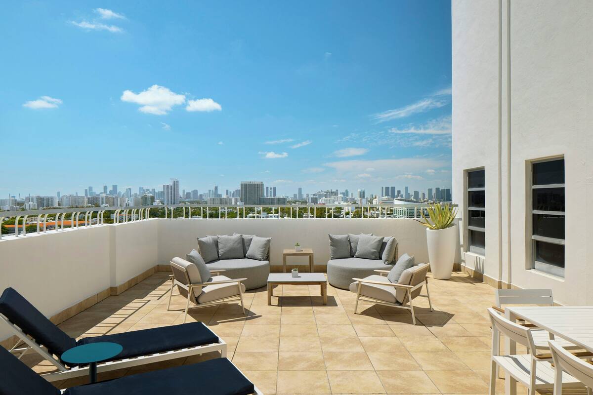 Une terrasse sur le toit offrant une vue sur la ville, aménagée avec des chaises longues, un canapé et une petite table.
