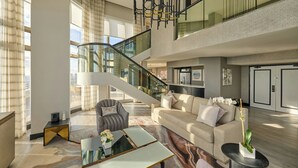 Un vaste espace de vie doté d’un haut plafond, d’un escalier et d’un lustre moderne.