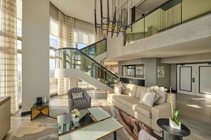 Ein geräumiger Wohnbereich mit hohen Decken, einer Treppe und einem modernen Kronleuchter.