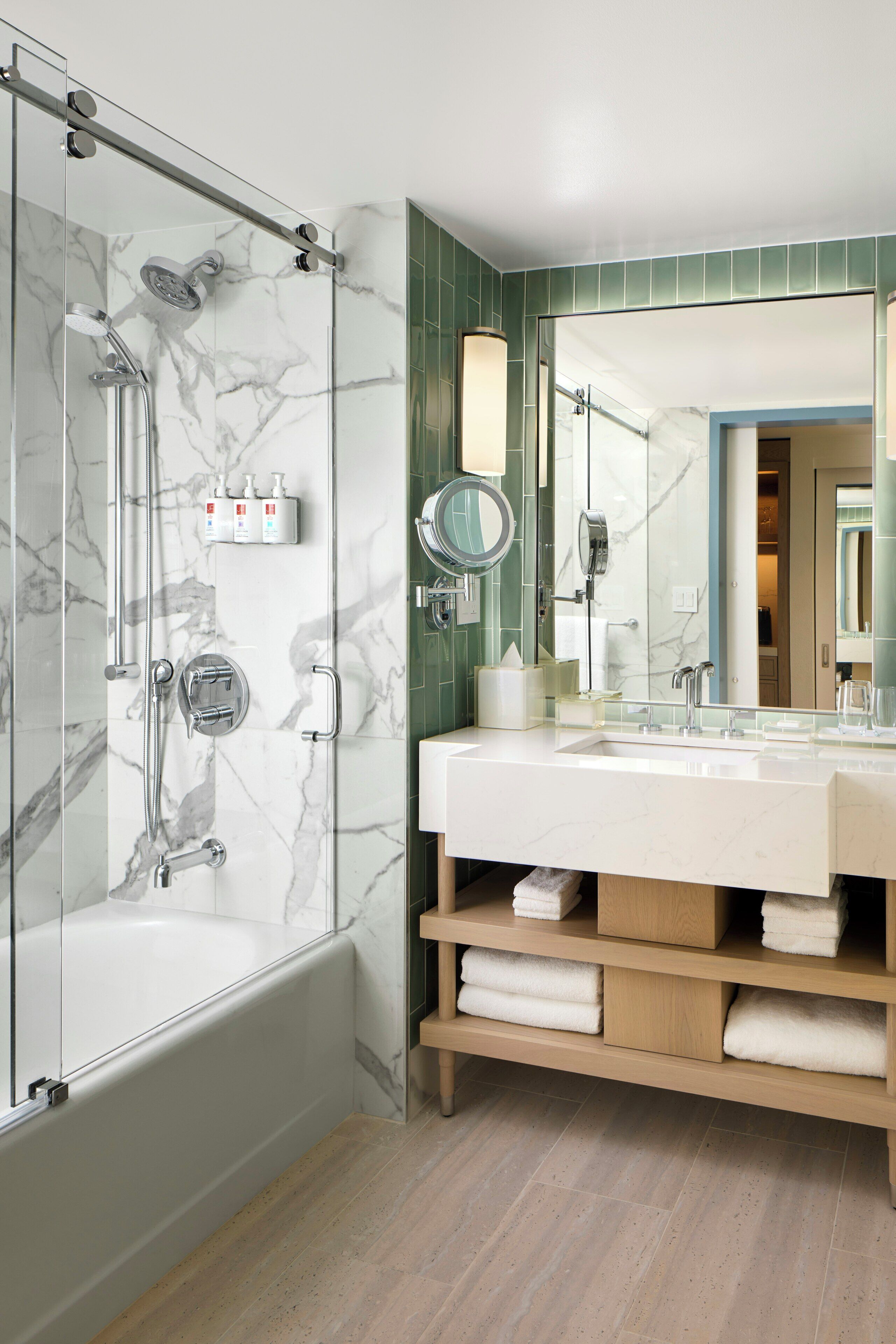 A modern bathroom with a glass-enclosed shower, a large vanity with a mirror, and neatly arranged towels.
