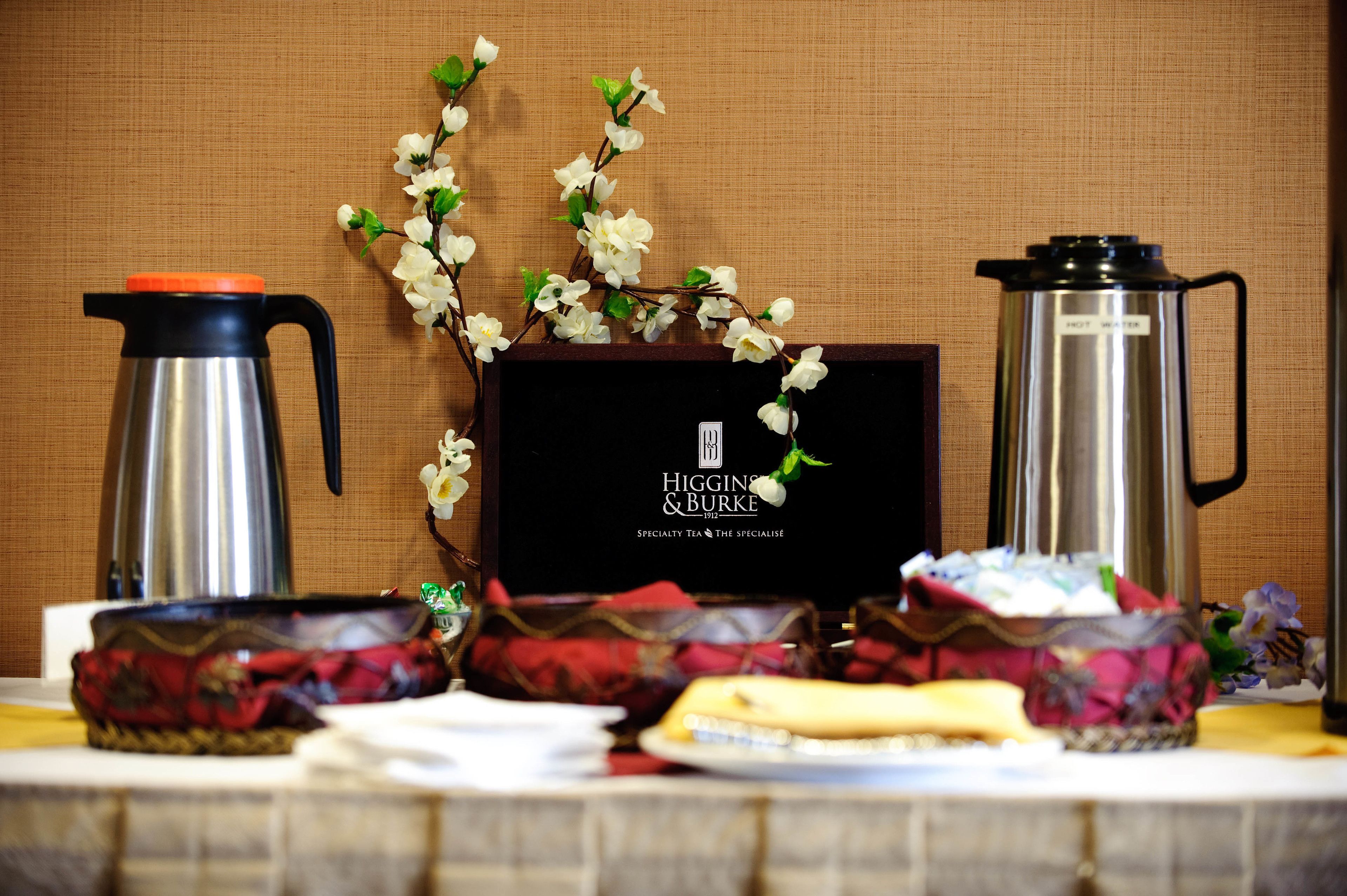 A table with a coffee maker, a teapot, and a decorative branch.