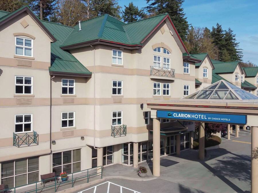 A multi-story hotel with a green roof, large windows, and a covered entrance.