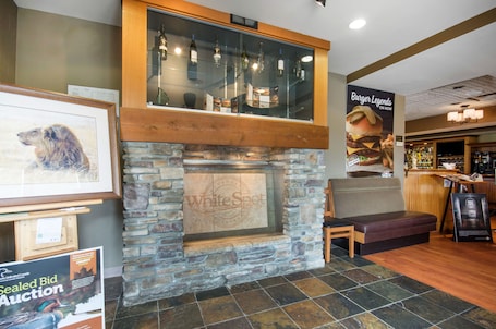A restaurant interior with a stone fireplace, wooden bench, and a bar area.