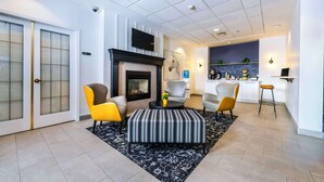 A modern living room with a fireplace, a television, and a kitchen area in the background. - Clarion Hotel & Conference Centre Abbotsford  (Abbotsford)