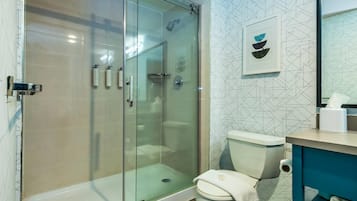 A bathroom with a glass-enclosed shower, a toilet, and a sink with a towel.