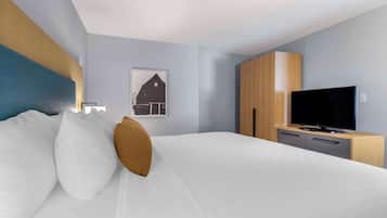 A hotel room with a bed, a television, a wooden cabinet, and a wall-mounted picture.