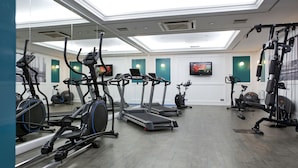 Un gimnasio con cintas de correr, bicicletas estáticas y máquinas de pesas.