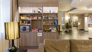 Un vestíbulo de hotel con zona de estar, kitchenette y mostrador de recepción.