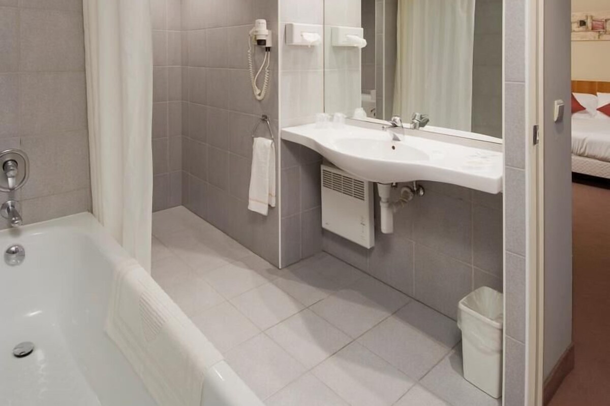 A modern bathroom with a bathtub, a sink, and a shower curtain.