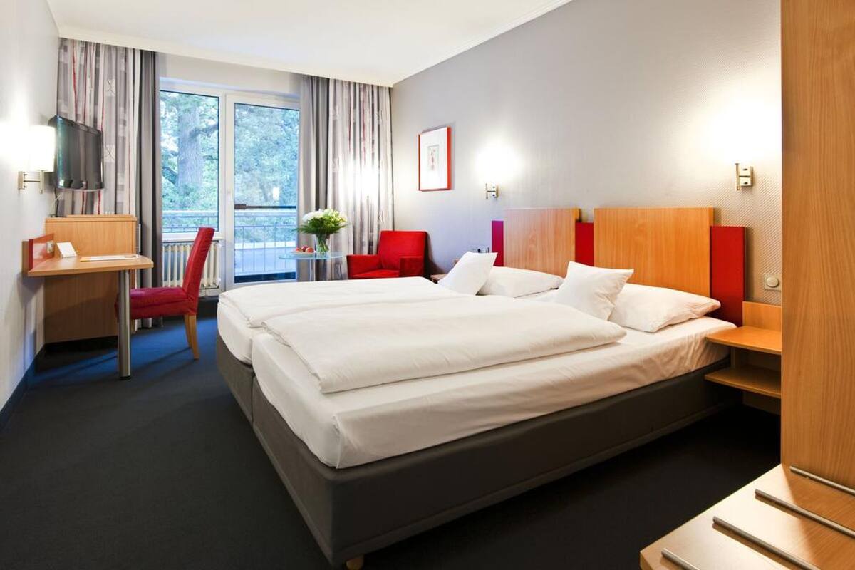 Une chambre d’hôtel avec un grand lit, un bureau, une chaise et un téléviseur.