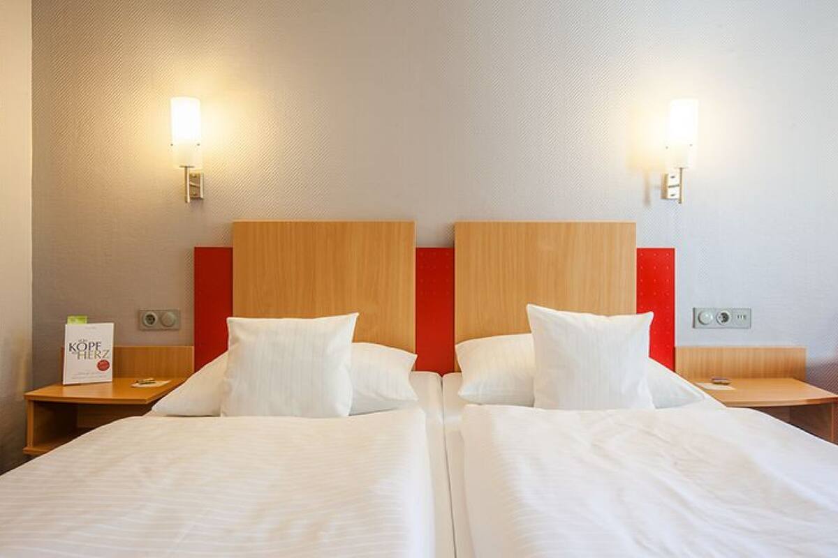 Une chambre d’hôtel avec deux lits, des têtes de lit en bois et des lampes de chevet.
