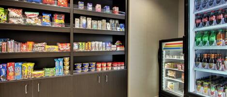 A snack and beverage refrigerator stocked with various items including chips, cereals, and sodas.