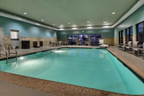 A large indoor swimming pool with a tiled floor, surrounded by chairs and a bench. - Holiday Inn Express & Suites - Interstate 380 at 33rd Avenue by IHG (Cedar Rapids)