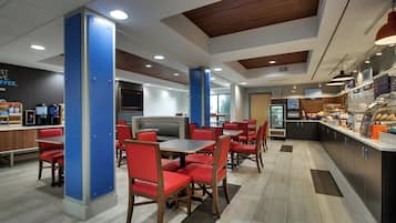 A modern cafe with seating arrangements, a counter with food items, and a refrigerator.