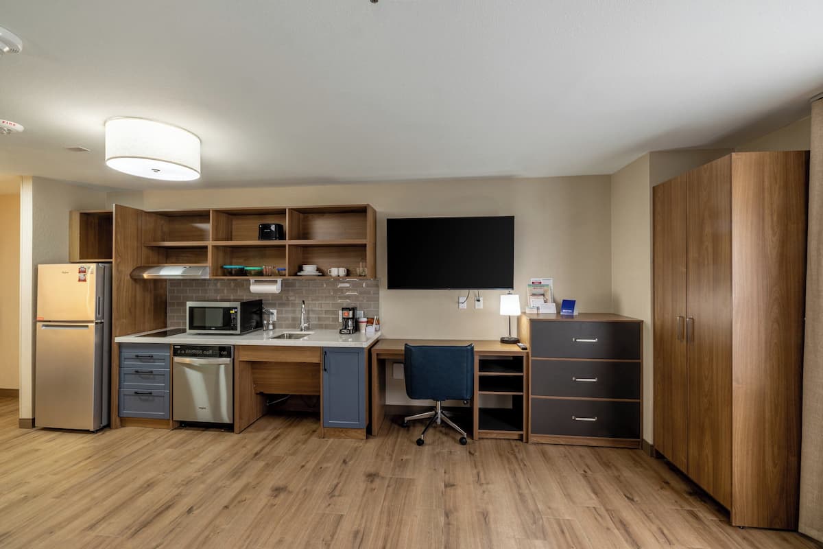 A compact kitchen with a microwave, refrigerator, dishwasher, and wooden cabinets.