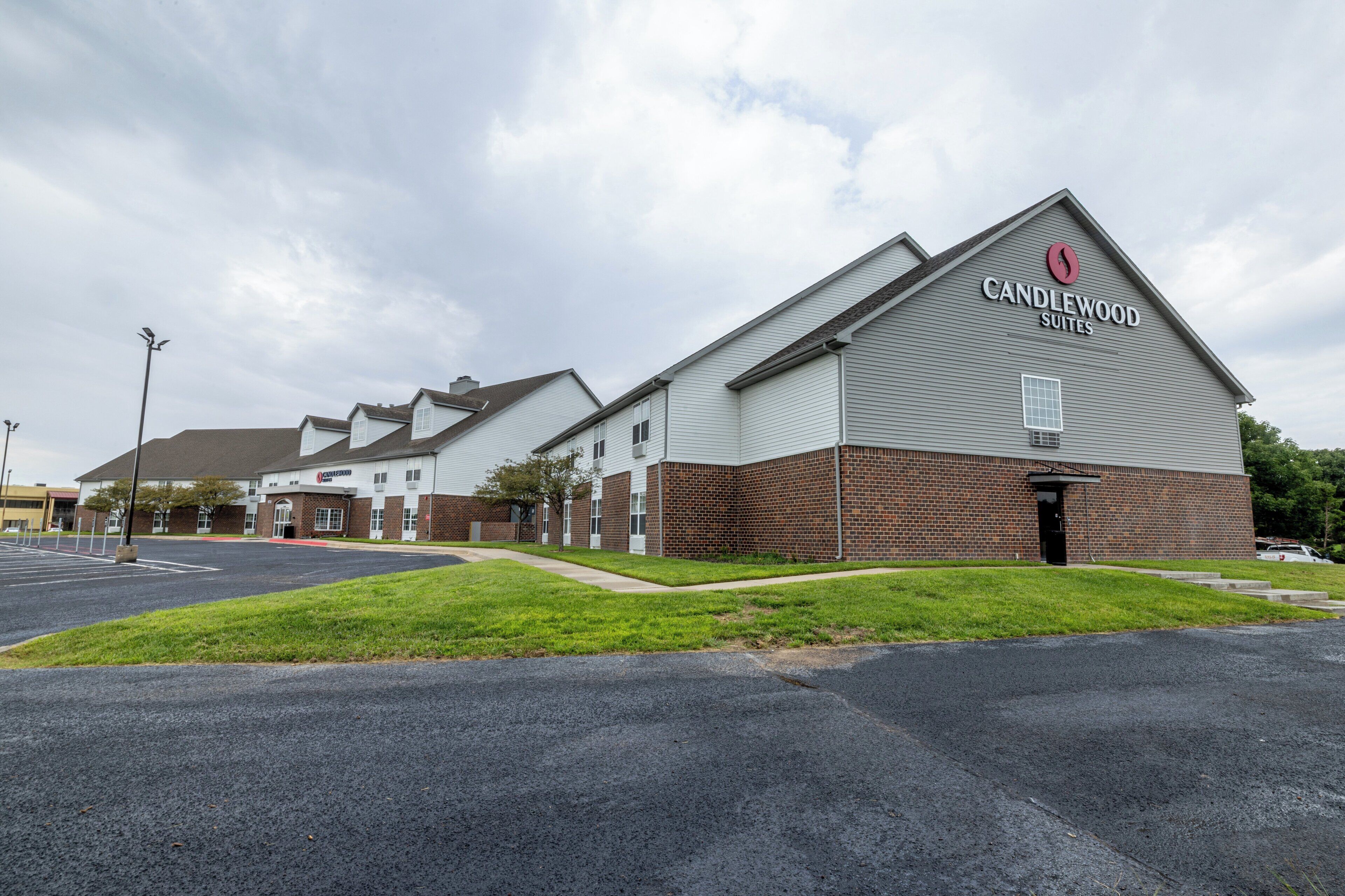 Et hotel ved navn Candlewood Suites med facade af mursten og en stor parkeringsplads.