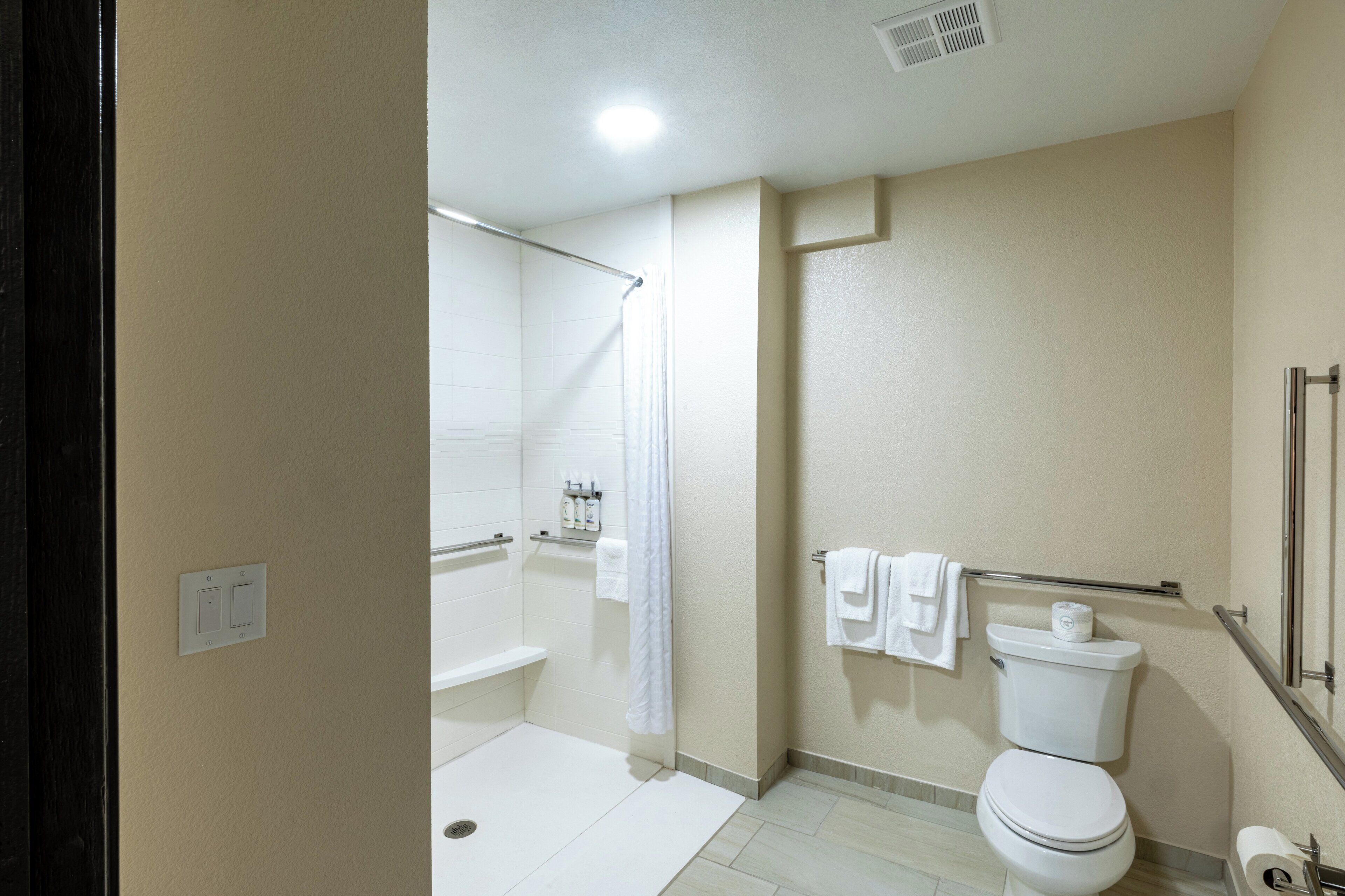 A bathroom with a shower, toilet, and a towel rack.