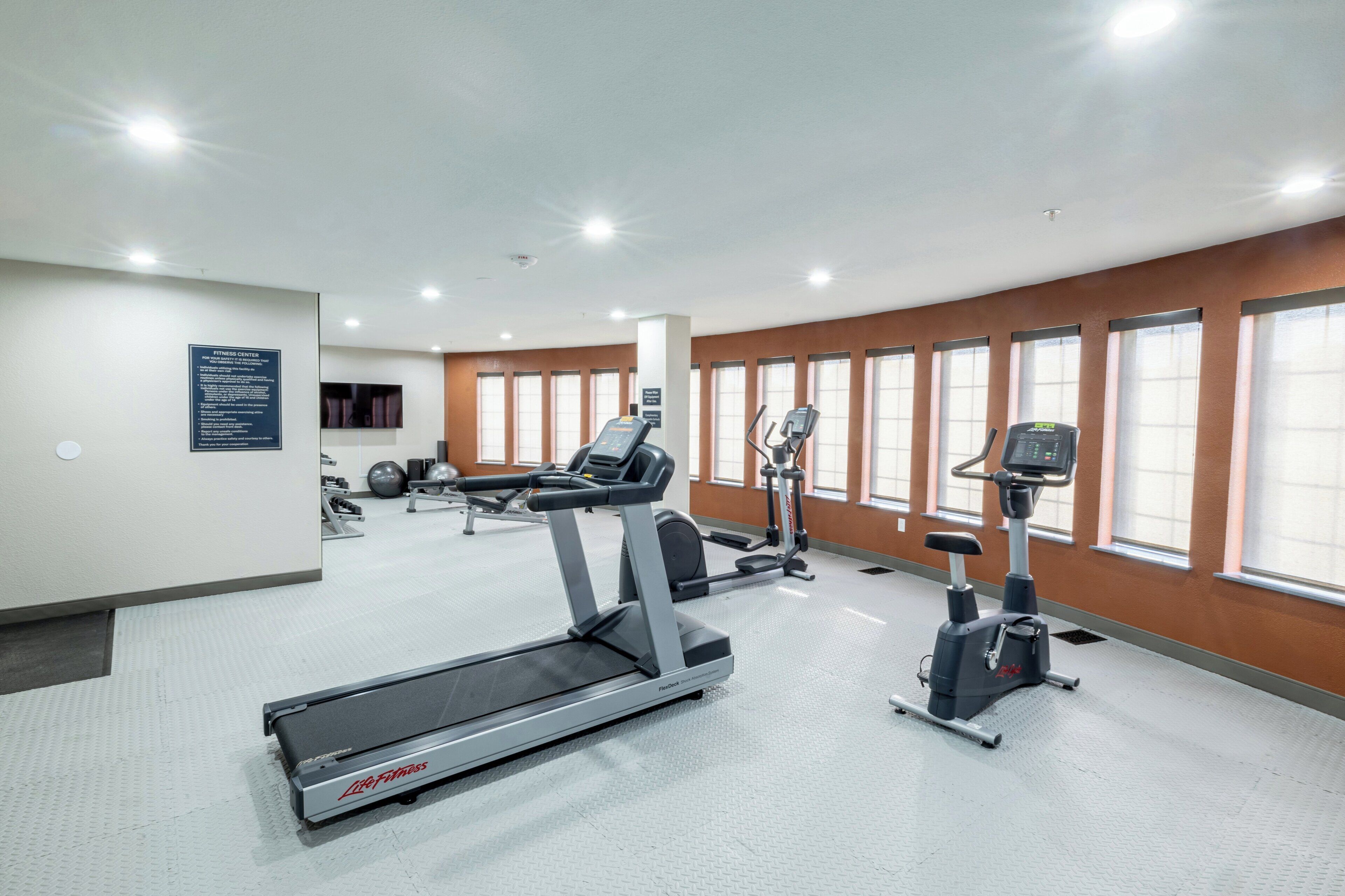 A fitness center with treadmills, elliptical machines, and free weights.