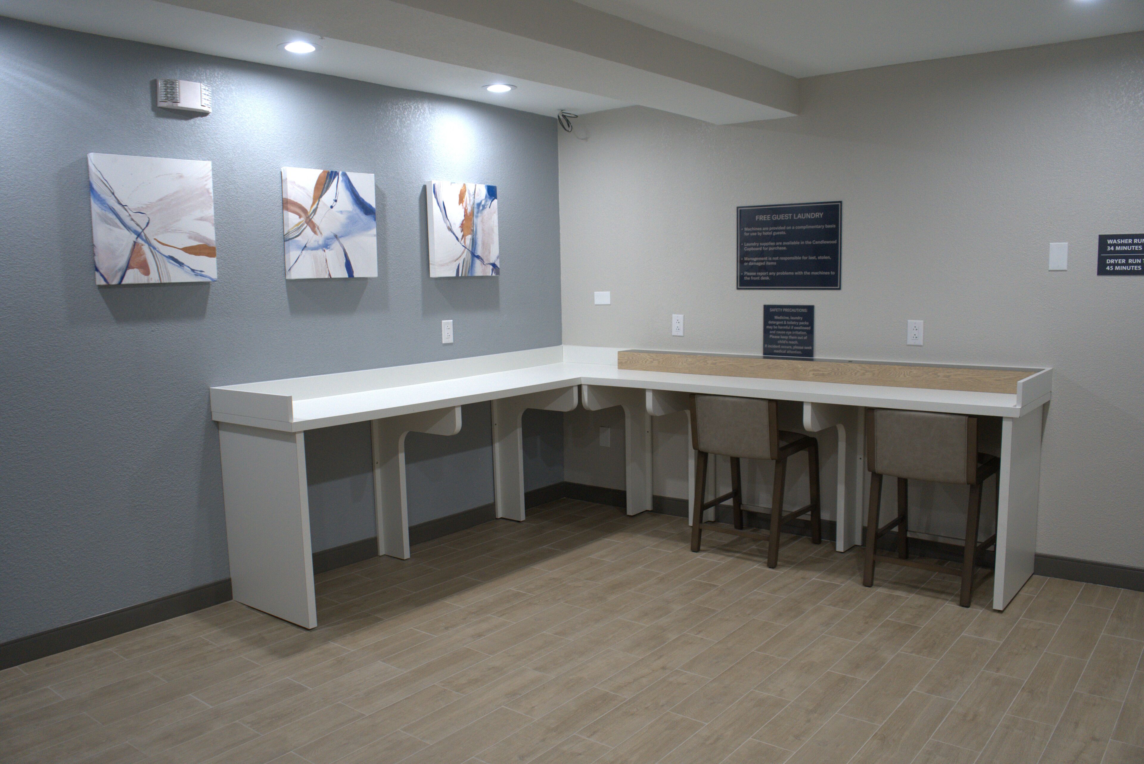 A reception area with a white reception desk, three chairs, and abstract art on the wall.