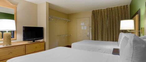 Habitación de hotel con dos camas, un televisor en una cómoda, un espejo y una ventana con cortinas.