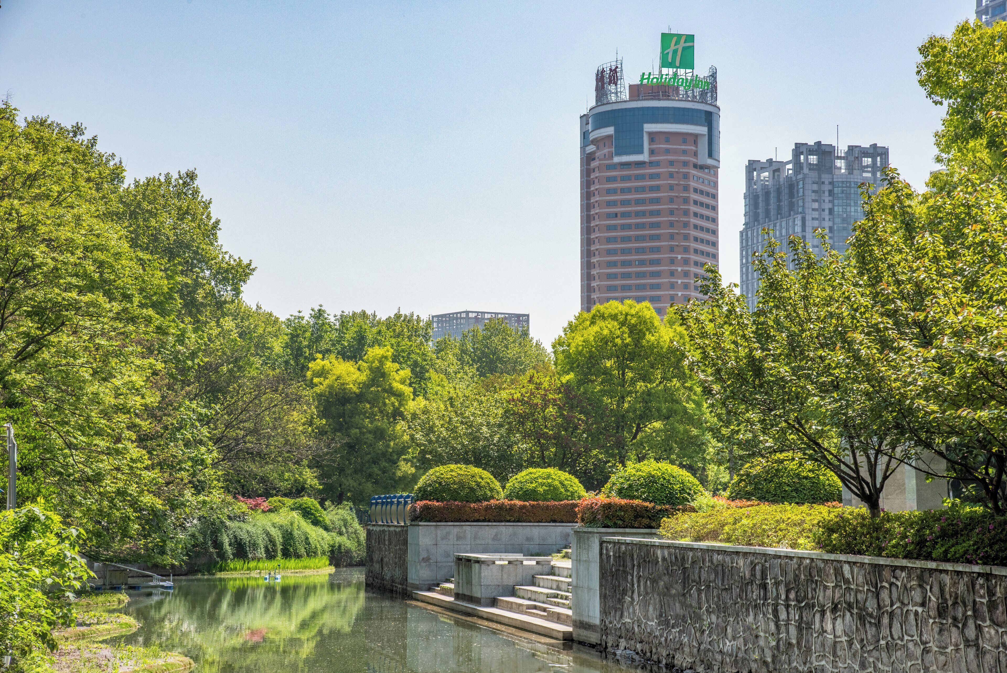 A riverside park with a stone wall, steps, and a small bridge.